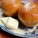 Golden brown dinner rolls on a blue and white plate.