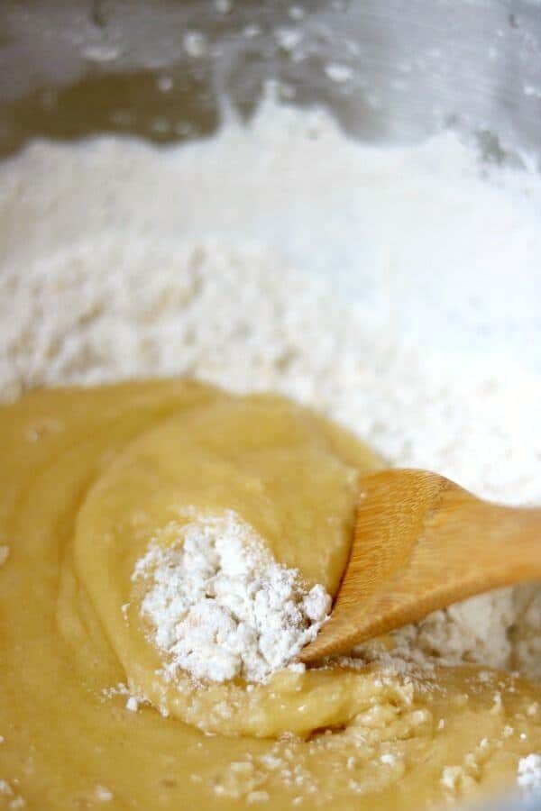 The best rolled sugar cookies recipe ever! So easy! Make sugar cookies that keep their shape plus tips and tricks to make them even better. From RestlessChipotle.com #sugarcookiesrecipe #rolledsugarcookies #bestsugarcookies A wooden spoon stirs flour into the soft dough for best rolled sugar cookies recipe