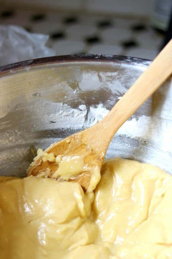 A wooden spoon stirs flour into the dough for best rolled sugar cookies recipe