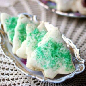 The best rolled sugar cookies ever - on an antique dish with gold trim. Cookies are cut out in Christmas tree shapes with green sugar. Recipe image