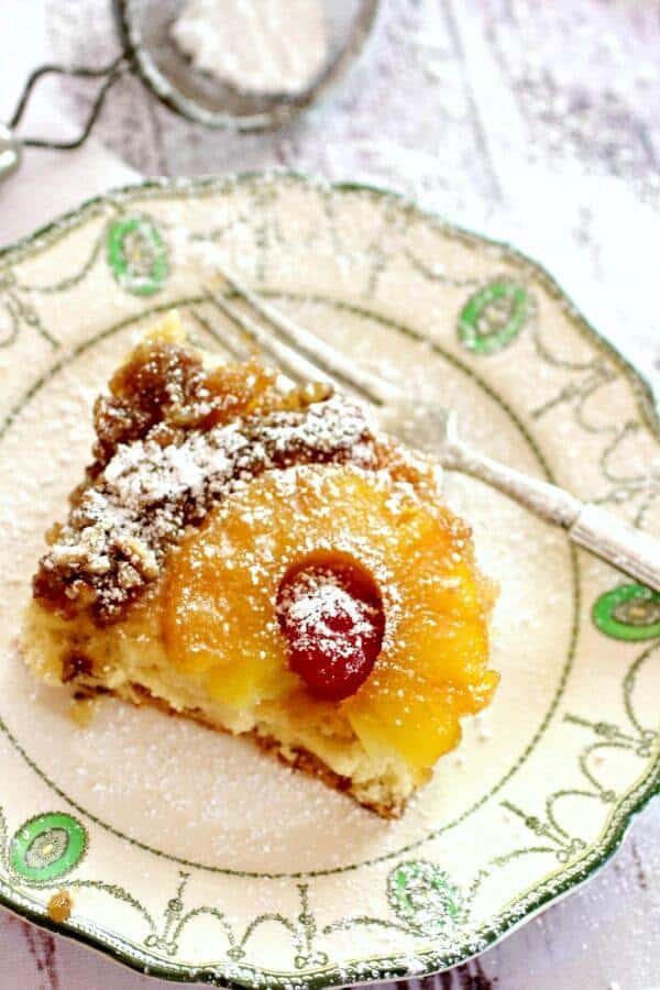 This easy pineapple upside down cake from scratch is updated from a vintage recipe. #restlesschipotle #pineapple #recipe #best #homemade #fromscratch #13x9 a square of pineapple upside down cake on a vintage white plate. Seen from the top the pineapple ring and cherry are clearly seen.