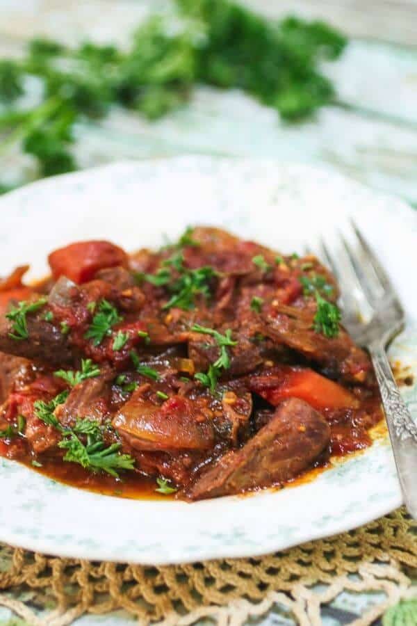 Closeup image of Swiss steak with green parsley on top.