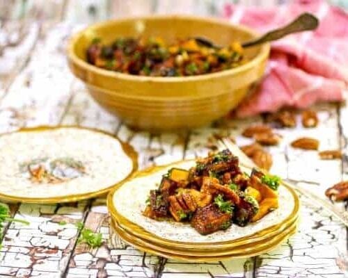 Golden sweet potatoes and pecans are diced into a salad and served on gold edged plates.