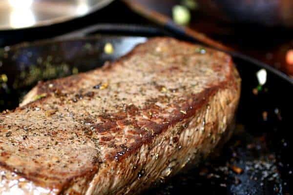 Searing the beef for pot roast in an iron skillet - the top has a rich, brown color from the searing.