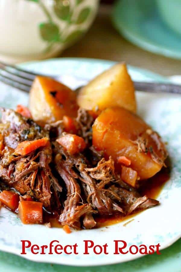 Pieces of tender, perfect pot roast, carrots, and potatoes are piled onto a vintage green and white plate with a fork and some crockery in the background. Title image for post.