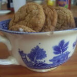 An antique cup filled with molasses cookies.