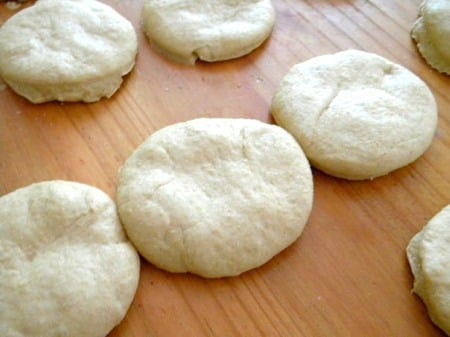 Unbaked hamburger buns on a table.