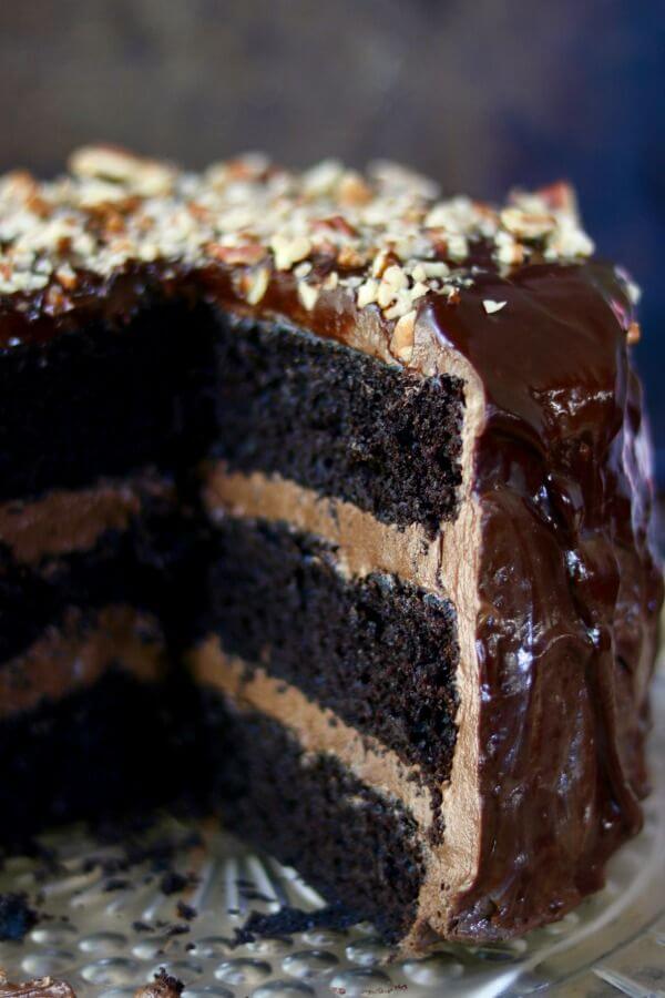 A 3 layer chocolate cake with a generous slice removed to show the layers.