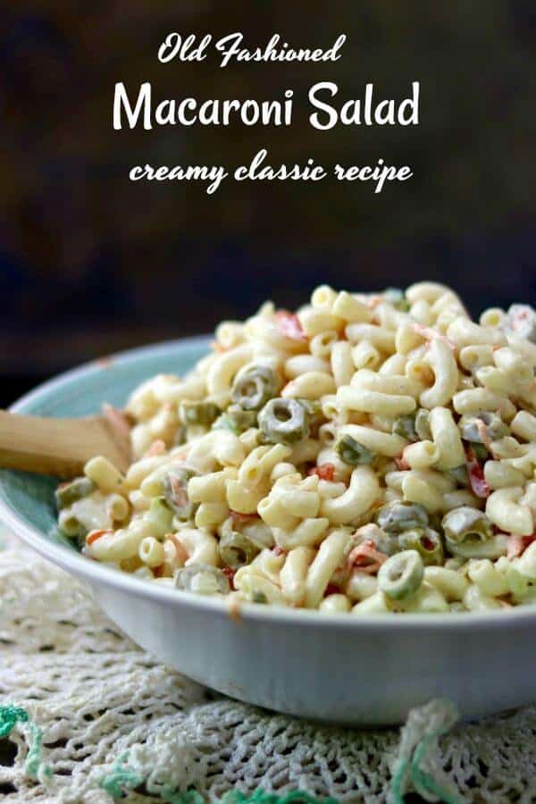 Bowl of macaroni, sliced olives, and other ingredients with creamy dressing on it.