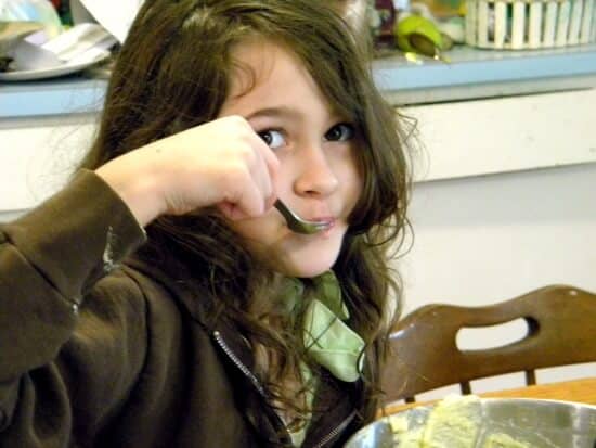 girl licking the frosting bowl.