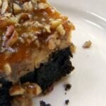 one praline cheesecake brownie. a rich brownie is covered with cheesecake then topped with pecan praline. Recipe image