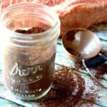Homemade Cocoa dry rub for beef is in a mason jar with a thick steak in the background.