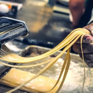 Homemade pasta being rolled by machine.