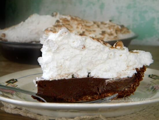A slice of chocolate pie with a fluffy marshmallow topping on a plate.