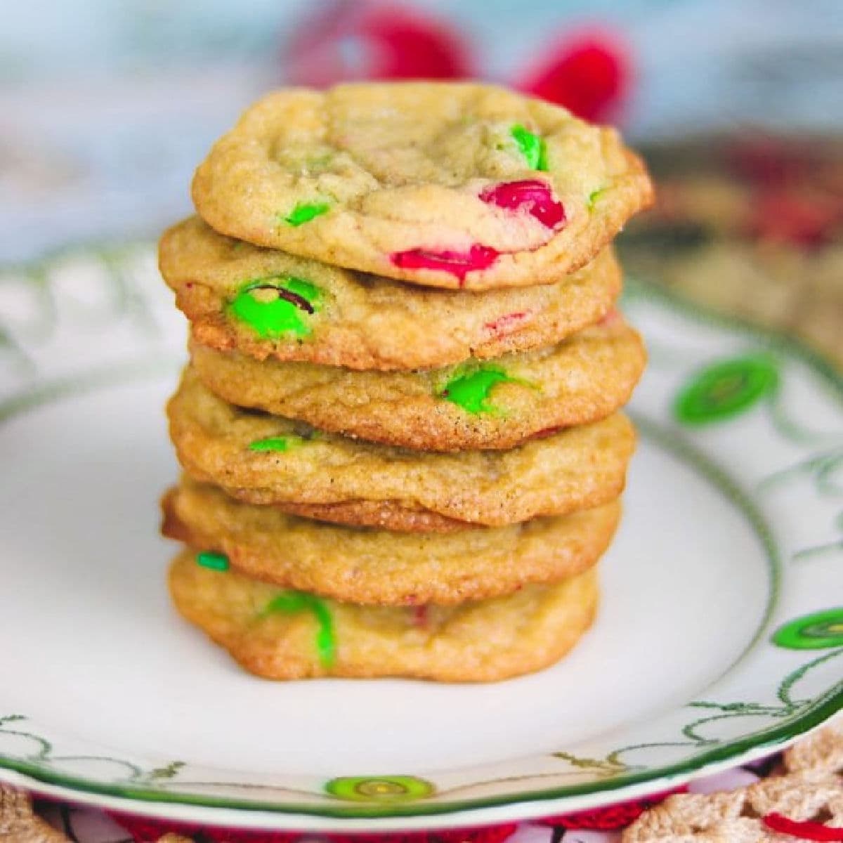 A stack of colorful m & m cookies on a white plate.