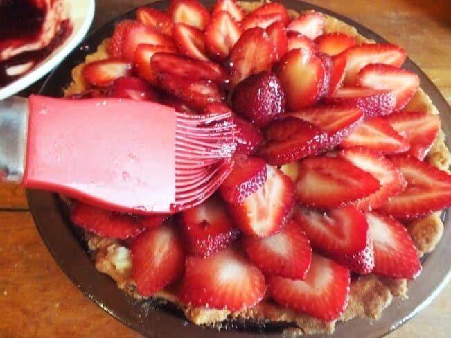 brushing on glaze to the strawberry and cream tart