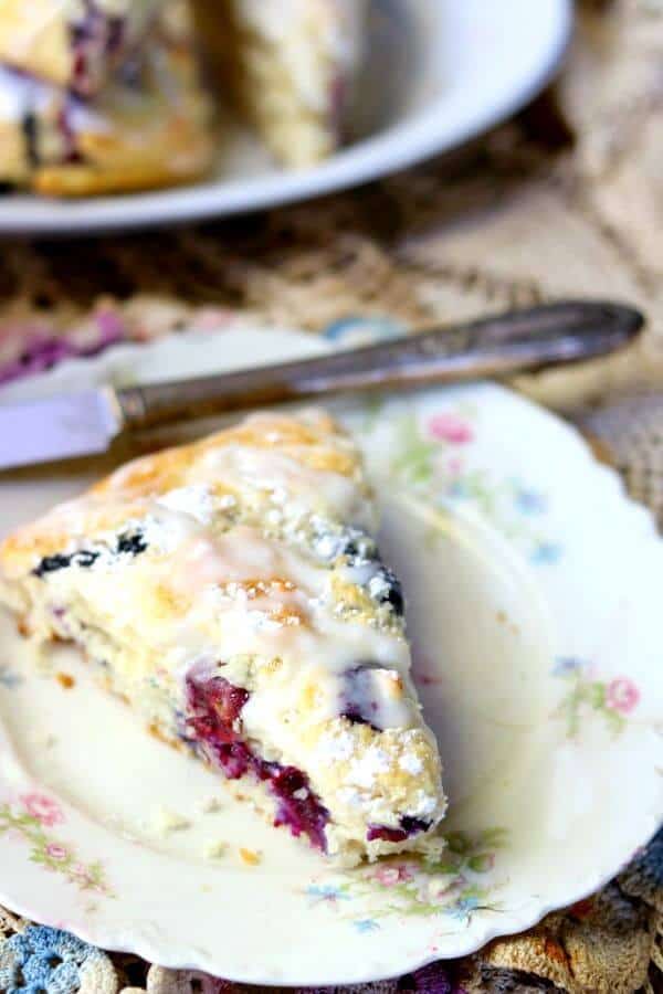 Closeup of lemon blueberry scones on an antique plate with floral edges.