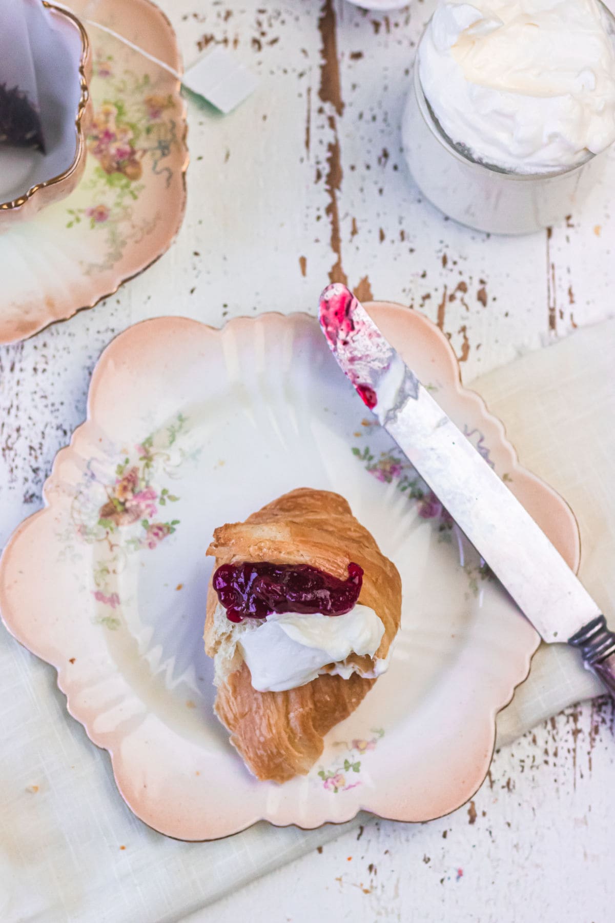 Decorative image - overhead view of a croissant with jam and cream on it.