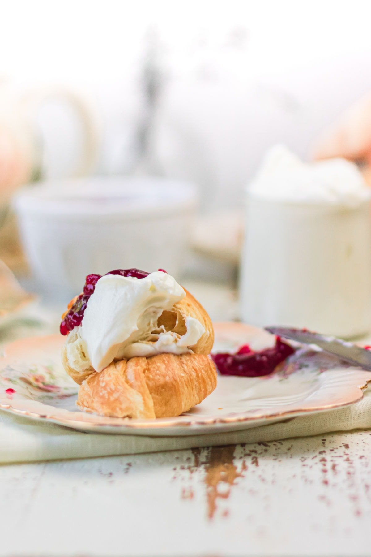 A croissant with jam and Devonshire cream spread on it.