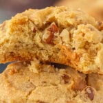 Closeup of a butter pecan toffee cookie with a bite removed.