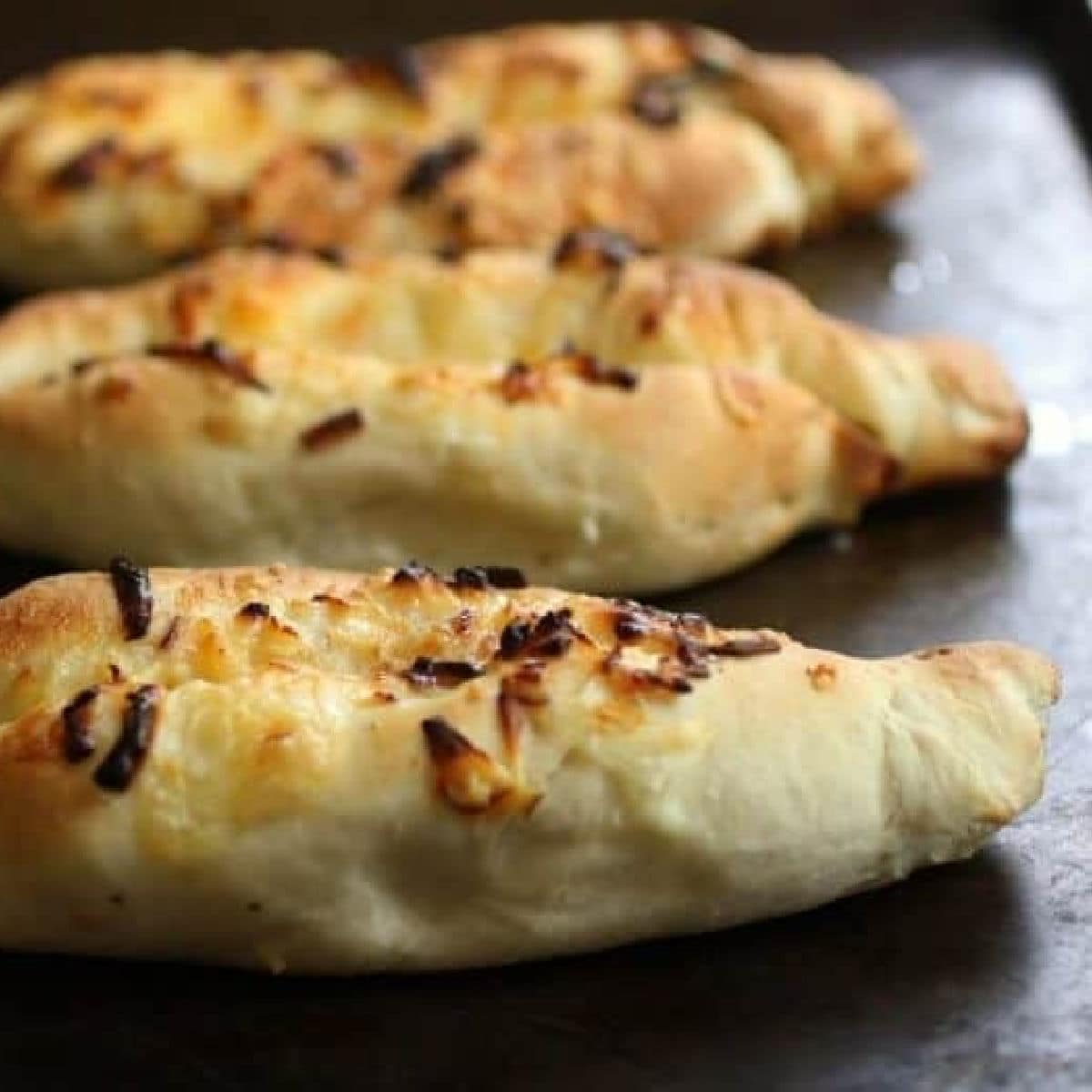 Three cheese filled rolls on a counter.