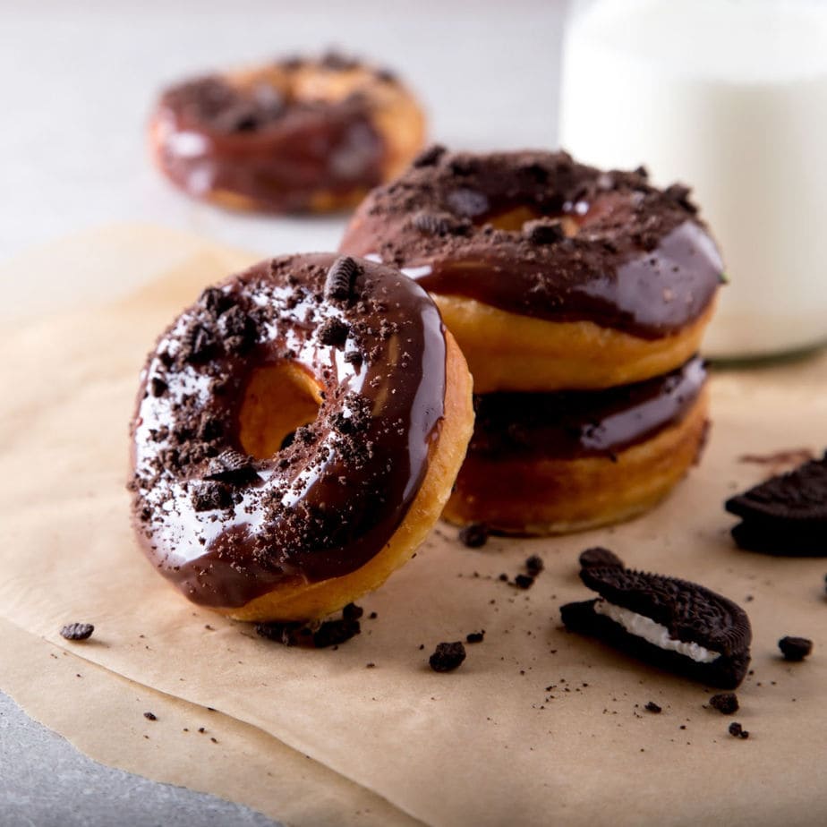 Finished donuts with chocolate glaze - glass of milk in the background.