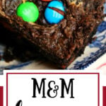 Brownies with M&Ms in the top on a blue and white plate.