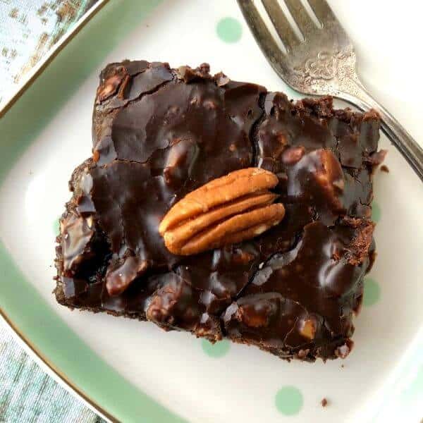 Top view of a square of Texas Sheet Cake with a pecan in the center and a silver fork to the side.