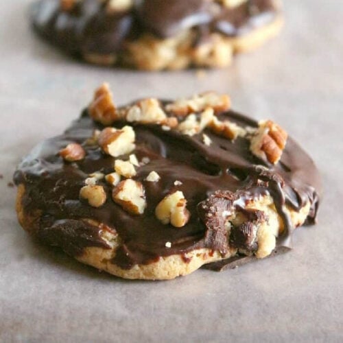 Big chewy chocolate chip cookie with ganache and pecans on top.