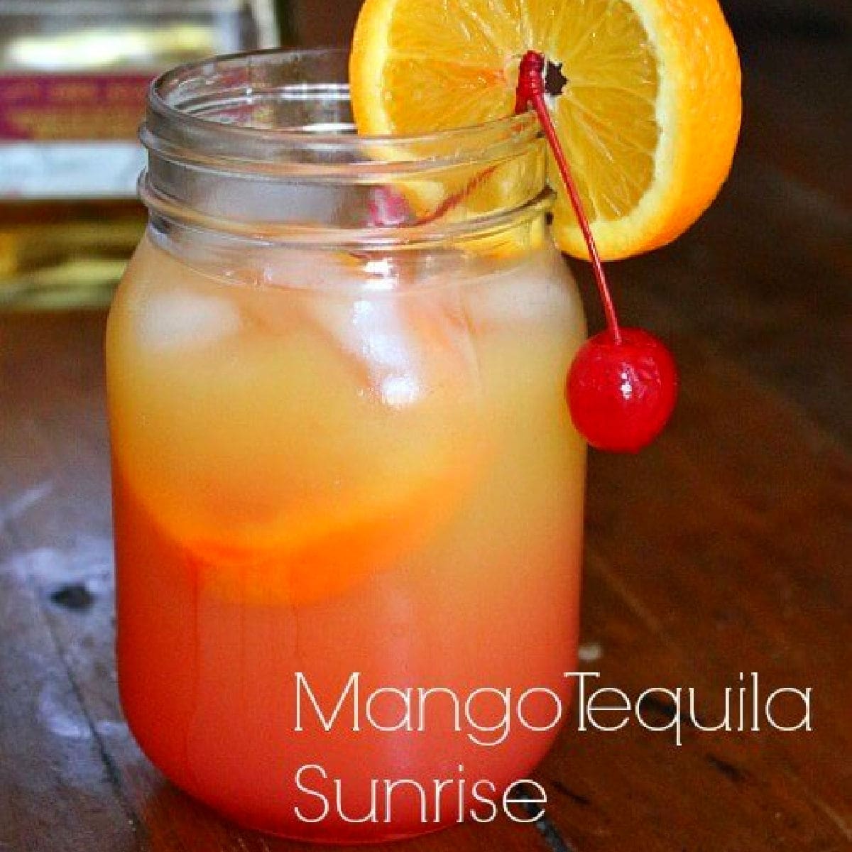 Closeup of a mango tequila sunrise garnished with an orange and a cherry.