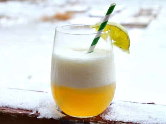 A glass of Barbados Punch with snow in the background.