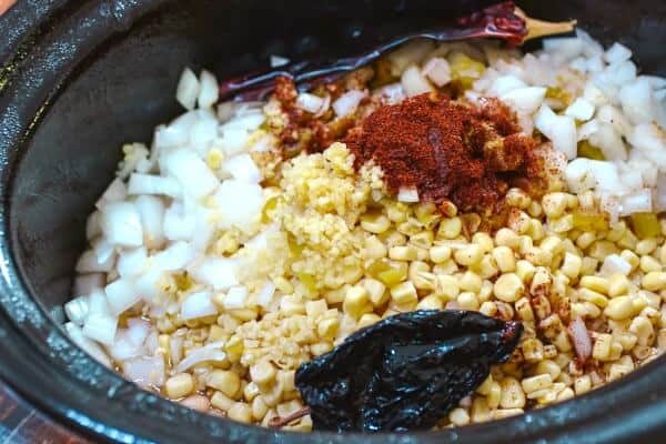 Corn, onions, and other ingredients for white chicken chili in a crockpot