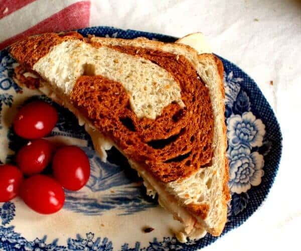 A sandwich made with a light bread with a dark red swirl.