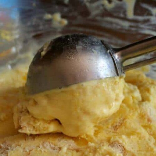 Scooping homemade ice cream from a freezer container.