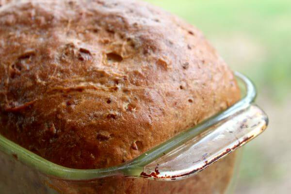 close up of the baked bread with a bumpy crust in a glass loaf pan.