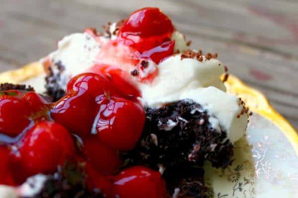 Chocolate cupcake cut in half with bright red cherry pie filling spilling out