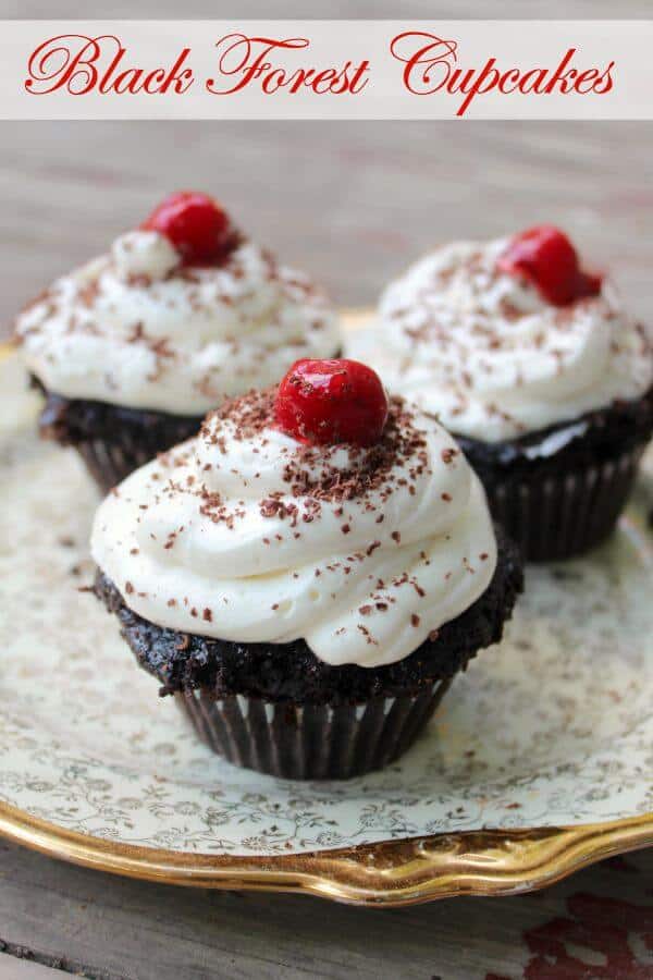 Black Forest Cupcakes with white whipped frosting and a cherry on top on a plate - title image