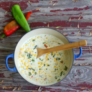 Overhead view of Hatch chile corn chowder in a large pot with a wooden spoon.