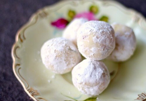 A stack of white chocolate truffles on an antique plate.