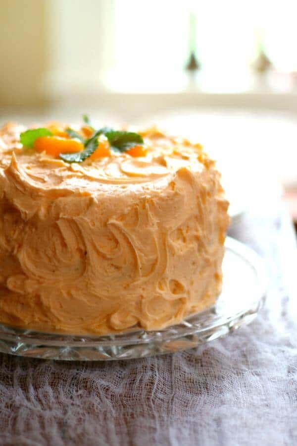 Orange layer cake is topped with a thick, fluffy orange frosting. From RestlessChipotle.com