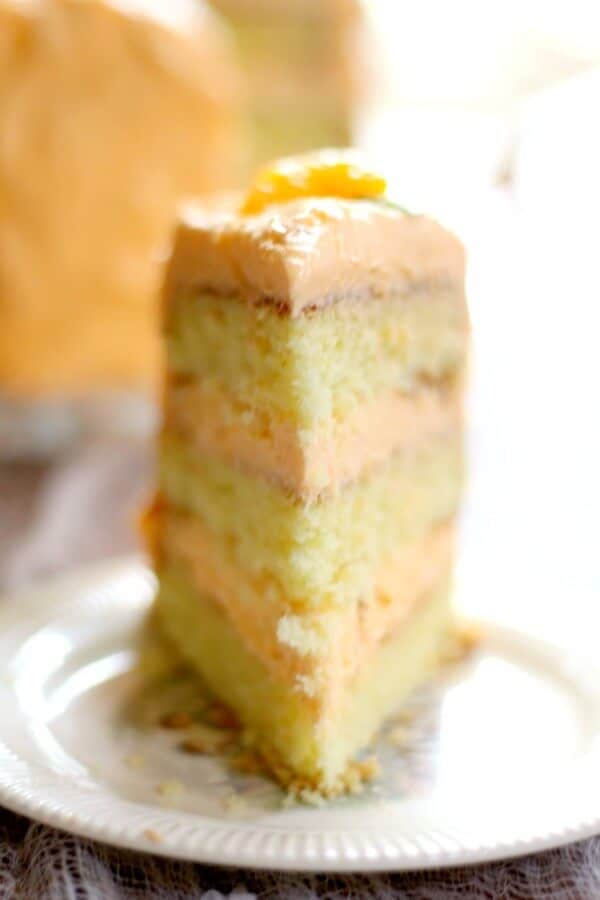 Tall orange layer cake is covered and filled with a thick, fluffy frosting with lots of orange flavor. From RestlessChipotle.com