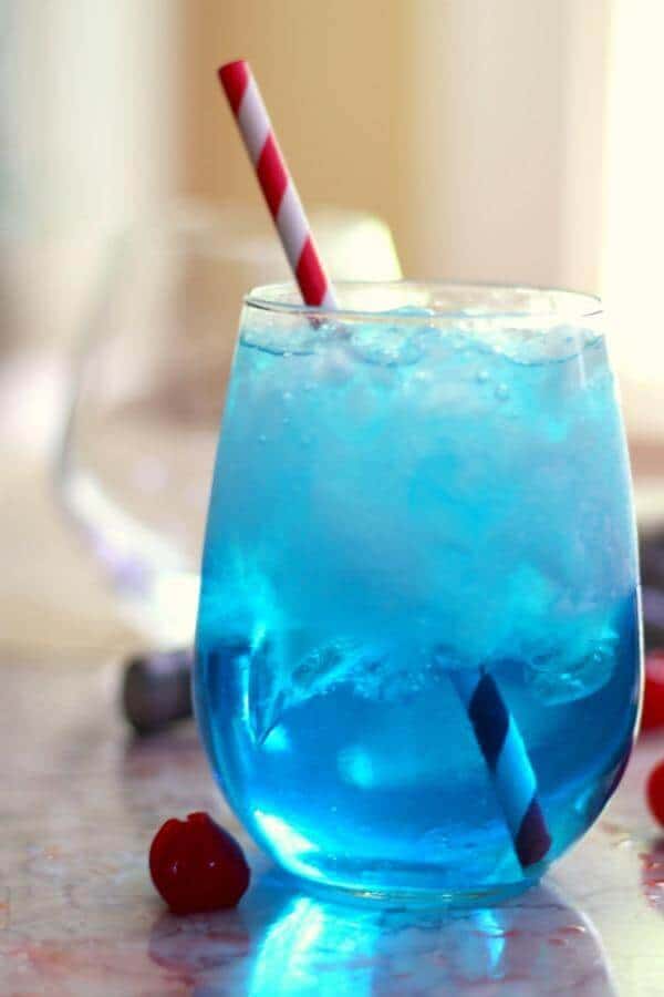 Bright blue cocktail with a red and white straw.