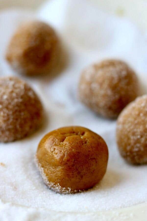 Balls of homemade peanut butter cookie dough being rolled in sugar.