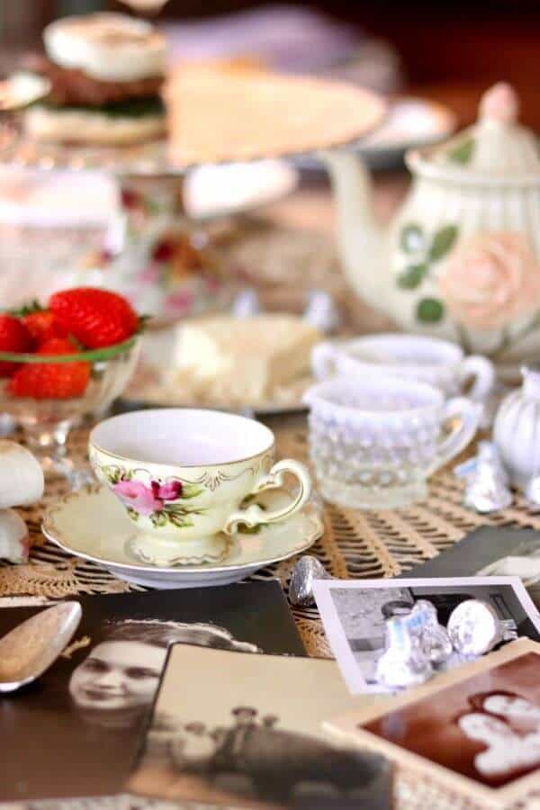 A vintage table setting with closeup of a teacup. Old pictures of moms are on the table.