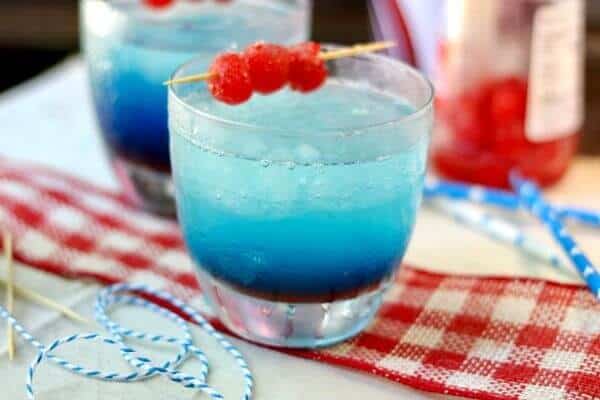 Red white and blue layered cocktail with a cherry garnish.