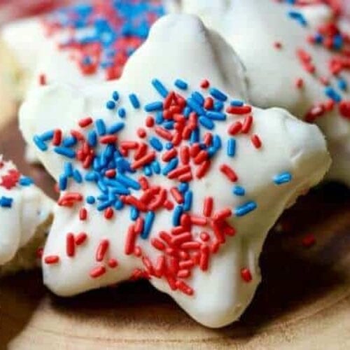 Closeup of a star shaped cake covered in white chocolate with red and blue sprinkles.