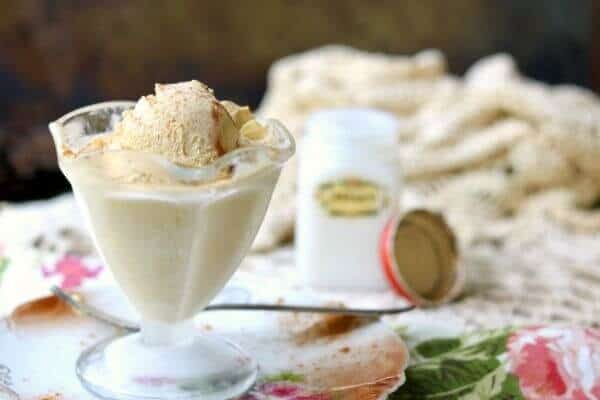 Homemade cinnamon gelato in a glass with a milk glass spice jar in the background.