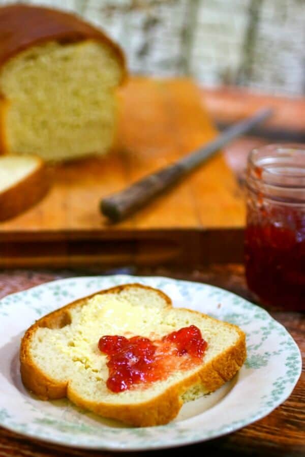 A slice of of homemade white bread spread with strawberry jam.