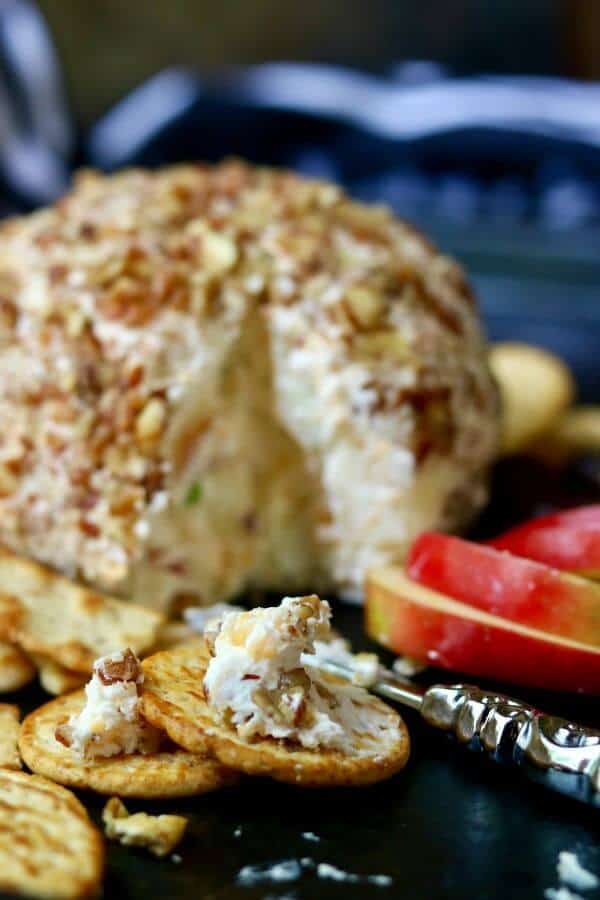 Apple cheddar cheeseball with a closeup of cheese mixture spread on a cracker.