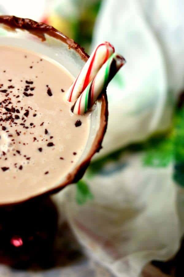 Closeup of a chocolate peppermint martini with grated chocolate on top, a chocolate rim, and peppermint sticks as garnish.